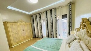 A bedroom with a bed, a wardrobe, and curtains. - kigali fine stay (Kigali)