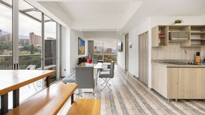A modern kitchen with a built-in microwave, wooden cabinets, and a large window offering a city view. - Borbon Suites (Medellin)