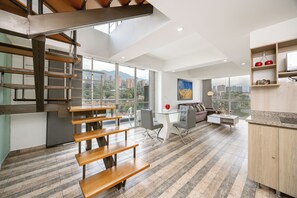 A modern interior with a staircase, dining area, and kitchen. - Borbon Suites (Medellin)