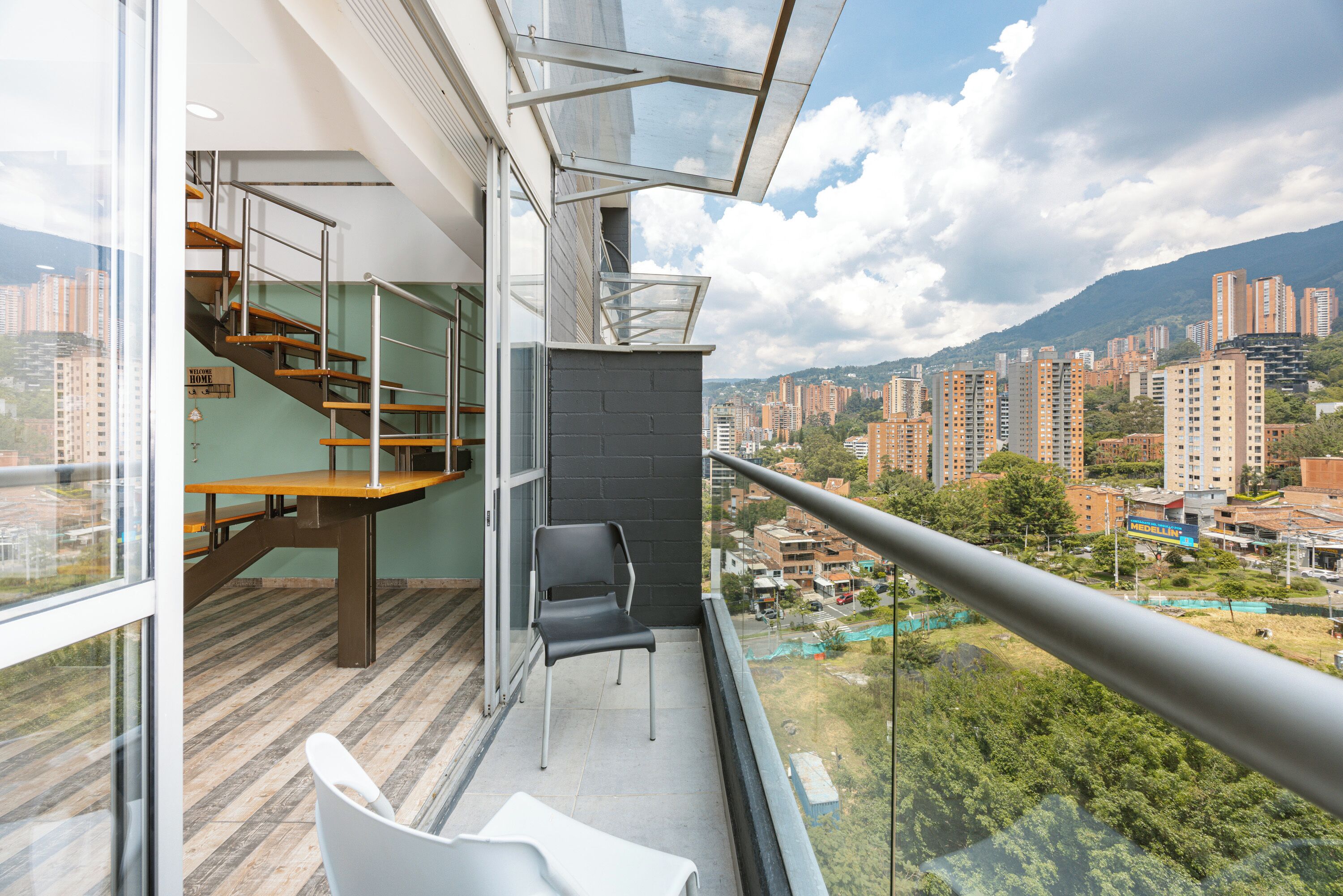 Ein Balkon mit Blick auf eine Stadtlandschaft, eine Treppe und ein Stuhl.