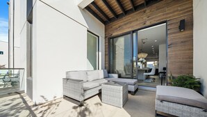 A modern outdoor seating area with wicker furniture and a concrete floor. - Paradise Living in Uptown Sarasota (Sarasota)