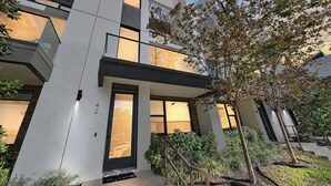 A modern building with a prominent entrance, a staircase leading to the entrance, and a well-maintained garden area with various plants. - Paradise Living in Uptown Sarasota (Sarasota)