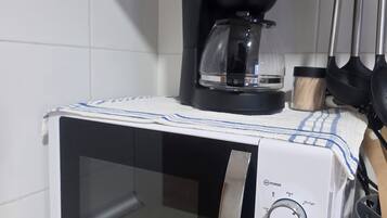 Un microondas con temporizador y ajustes de potencia, una cafetera y un organizador de utensilios de cocina.