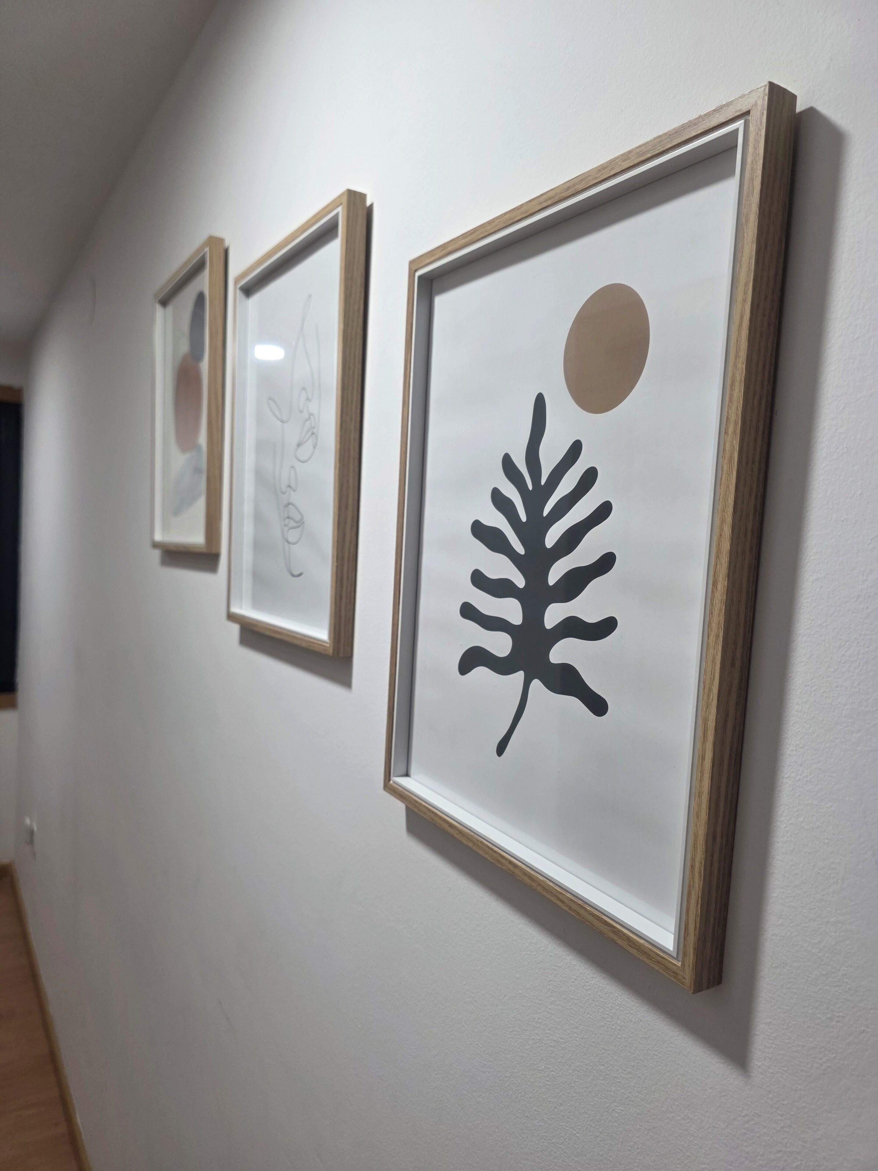Trois œuvres d’art encadrées sont accrochées au mur.