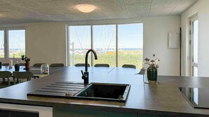 Eine moderne Küche mit einer großen Kochinsel, einer integrierten Spüle und Blick auf Segelboote durch große Fenster.