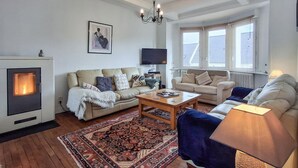 A living room with a fireplace, two sofas, a coffee table, and a patterned rug. - 5 bedroom lovely home in Saint-Martin-des-Champ (Saint-Martin-des-Champ)