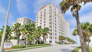 A multi-story hotel with a modern design, featuring balconies on each floor, surrounded by palm trees and a clear sky. - Amazing Oceanfront 3 bed 3 bath Condo (Daytona Beach Shores)