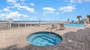 A pool area with a hot tub, lounge chairs, and a view of the ocean. - Amazing Oceanfront 3 bed 3 bath Condo (Daytona Beach Shores)