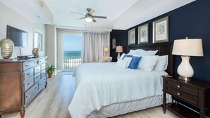 A bedroom with a large bed, a ceiling fan, a dresser, and a view of the ocean. - Amazing Oceanfront 3 bed 3 bath Condo (Daytona Beach Shores)