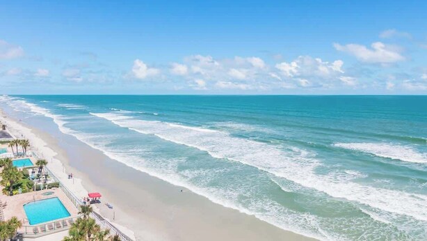 A beach with a swimming pool and beach chairs. - Amazing Oceanfront 3 bed 3 bath Condo (Daytona Beach Shores)
