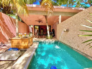 A pool area with a wooden bar, chairs, and a ceiling fan.