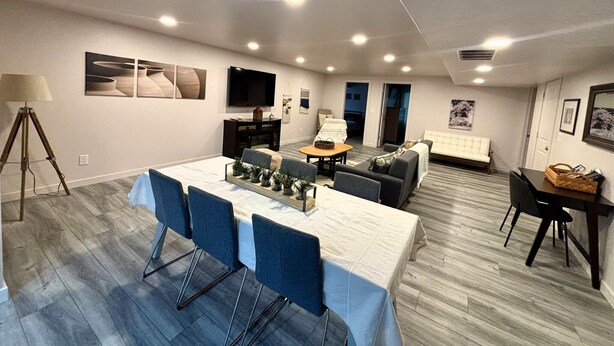 A modern living room with a dining area, a flat-screen TV, and a sofa.