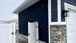 A residential building with a white garage door, a stone wall, and a dark blue exterior wall.
