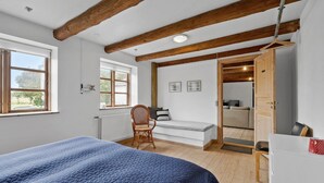 Un dormitorio con una cama, una silla, un banco y un armario.