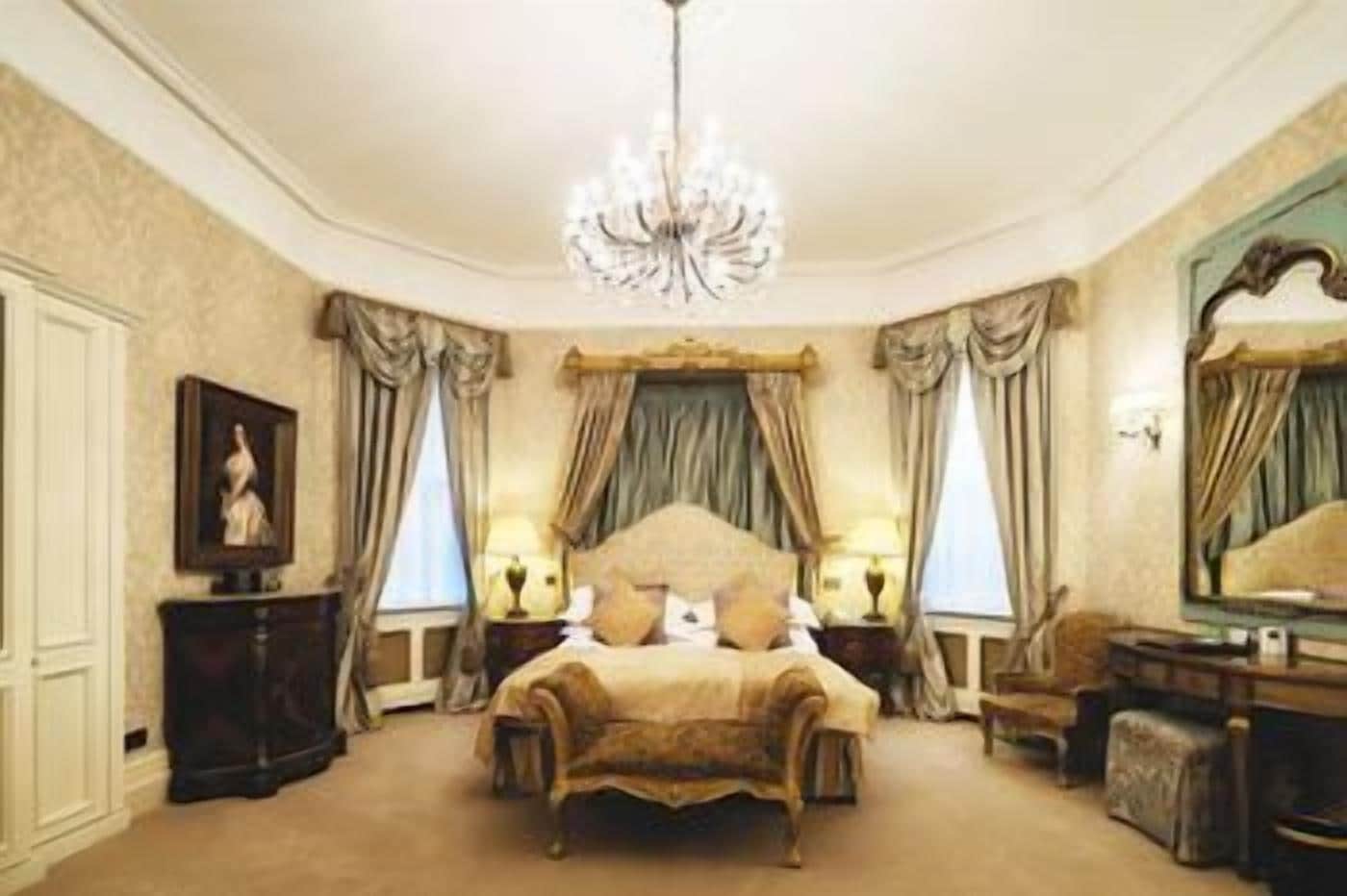 A bedroom with a large bed, a chandelier, and a mirror.