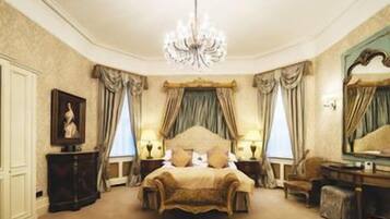 A bedroom with a large bed, a chandelier, and a mirror.