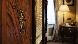 A wooden door with a brass angel door knocker, a window with blinds, a lamp, and a framed picture on the wall. - Fitzpatrick Castle Hotel (Dublin)