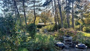 A forested outdoor area with a barbecue grill, a stone table, and a small pond. - Newly built holiday home with a fjord view (Orø)