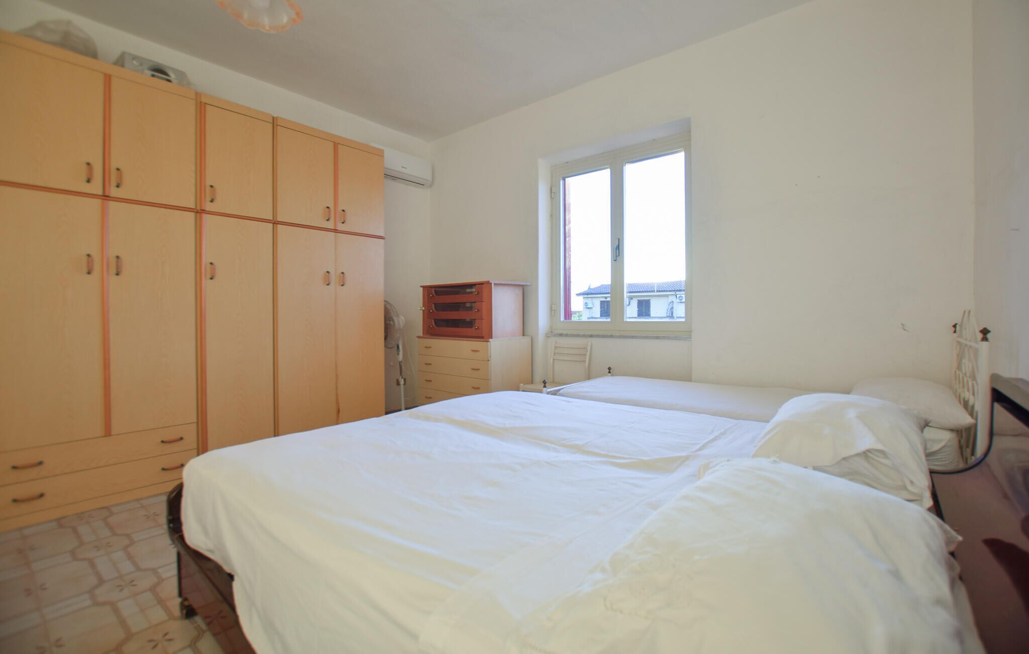 Een slaapkamer met twee bedden, een raam en een kledingkast.