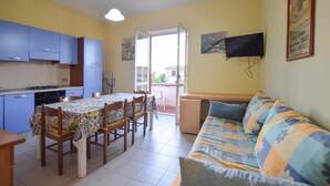 Un espacio habitable compacto con una mesa de comedor, sillas, un sofá, un televisor y un balcón con vistas.