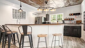 A kitchen with a bar area, bar stools, a refrigerator, a microwave, and a window with a view of greenery. - Lakefront - Sleeps 16 - Two Kitchens - Play Room (Union City)