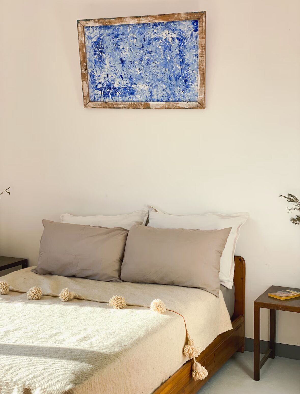 A bedroom with a bed, pillows, a blanket, and a small bedside table.