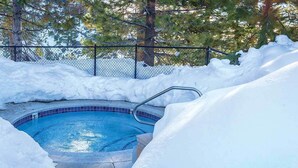 A hot tub surrounded by snow, with a fence and trees in the background. - Charming 2-bedroom condo with fitness room and AC in gorgeous Stateline (Stateline)