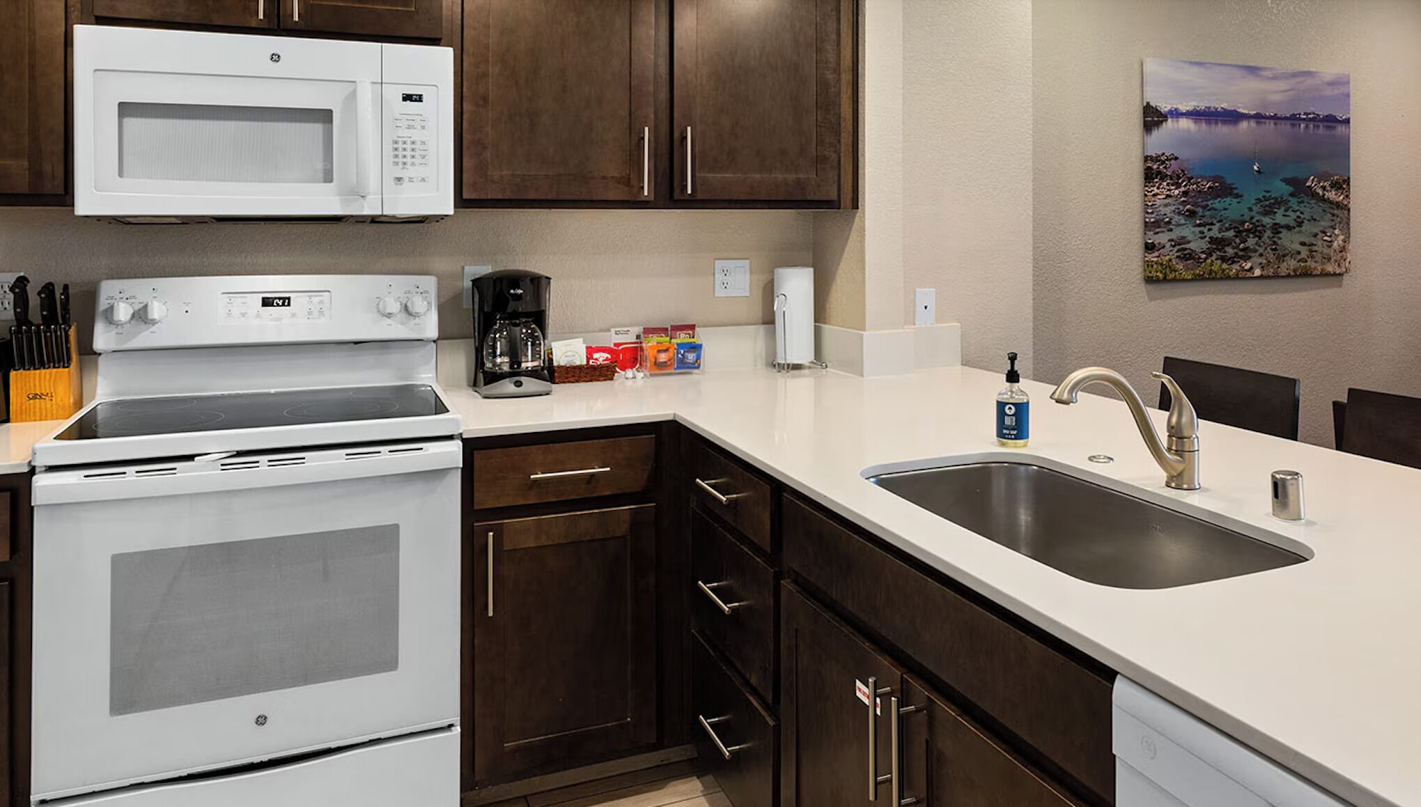A modern kitchen with a stove, microwave, sink, and cabinets.