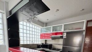 A modern kitchen with a red countertop, black cabinets, and stainless steel appliances. - Apartment in exclusive area - 5 min Airport (Chiclayo)