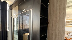 A modern closet with sliding doors and built-in shelves, a small wooden table, and a view of a living area with a sofa and decorative pillows. - Apartment in exclusive area - 5 min Airport (Chiclayo)