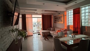 A modern living room with a sofa set, a dining table, and a TV mounted on the wall. - Apartment in exclusive area - 5 min Airport (Chiclayo)