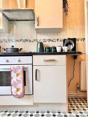 A kitchen with a stove, oven, microwave, and a coffee maker on the countertop.