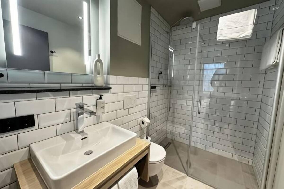 A modern bathroom with a white sink, mirror, and shower.