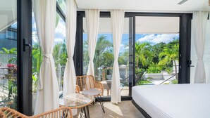 A balcony with a bed, wicker furniture, and a glass door leading to a pool. - L'Avventura Unit 4 Terrace Adults-Only Full Kitchen King Studios (Tamarindo)