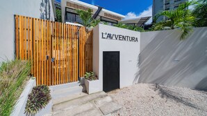 A modern building with a wooden fence and a sign that reads "L'AVENTURA". - L'Avventura Unit 4 Terrace Adults-Only Full Kitchen King Studios (Tamarindo)
