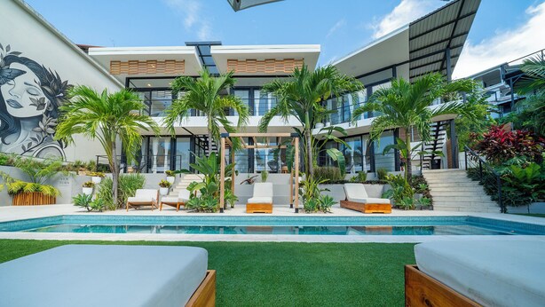 A modern outdoor pool area with lounge chairs, artificial grass, and a mural on the wall. - L'Avventura Unit 4 Terrace Adults-Only Full Kitchen King Studios (Tamarindo)