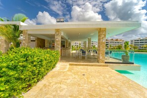 A modern hotel with a pool area, outdoor seating, and a covered patio. - Peace on The Beach in Punta Cana (Punta Cana)
