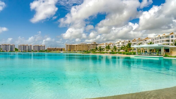 A resort with a large pool, multiple hotel buildings, and a clear blue sky. - Peace on The Beach in Punta Cana (Punta Cana)