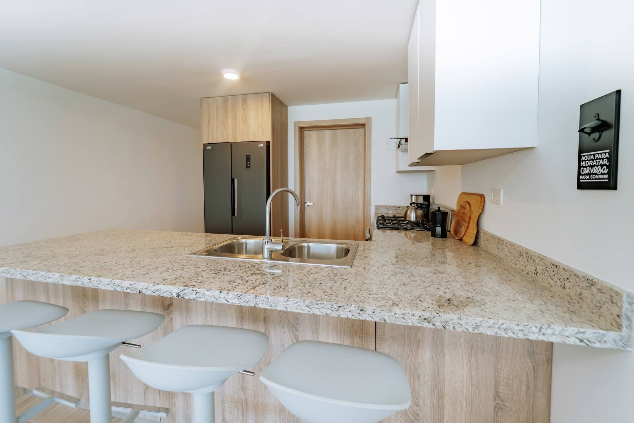 Une cuisine moderne dotée de plans de travail en granit, d’appareils électroménagers en acier inoxydable et de tabourets de bar.