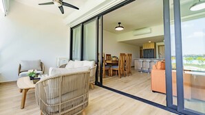 A modern living room with a large sliding glass door leading to a kitchen and dining area. - Peace on The Beach in Punta Cana (Punta Cana)