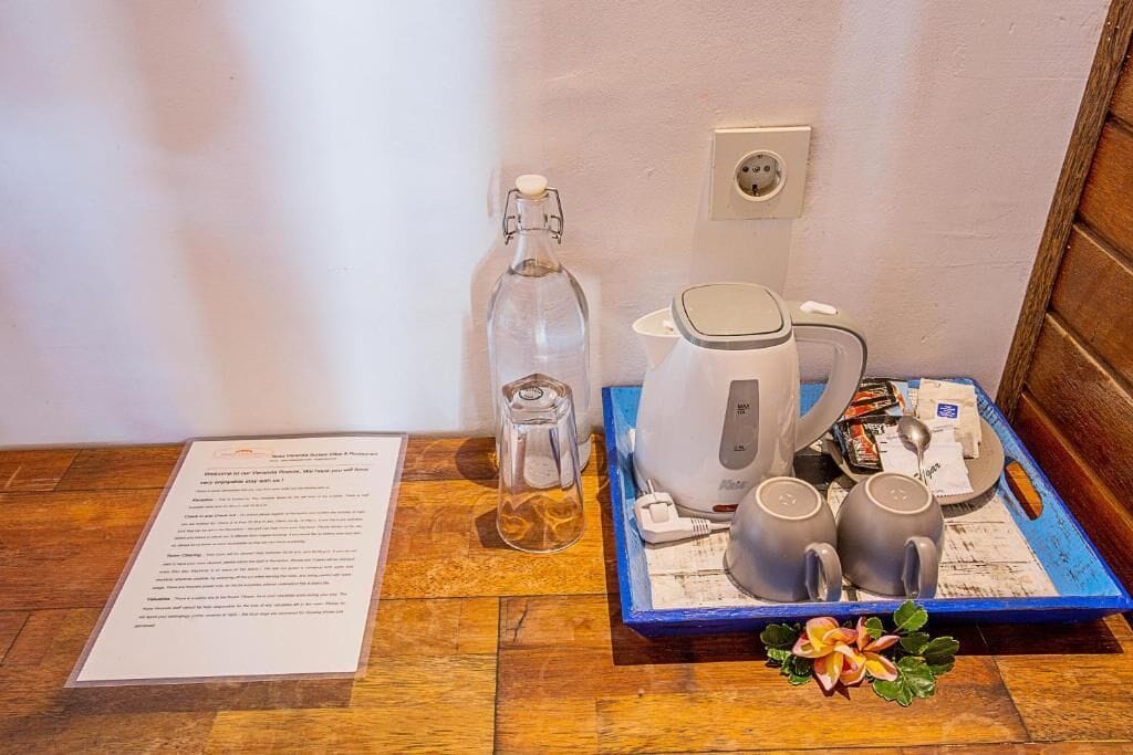 Un desayuno servido con una tetera, dos tazas, una jarra de vidrio y una bandeja con alimentos para el desayuno, todo sobre una mesa de madera.