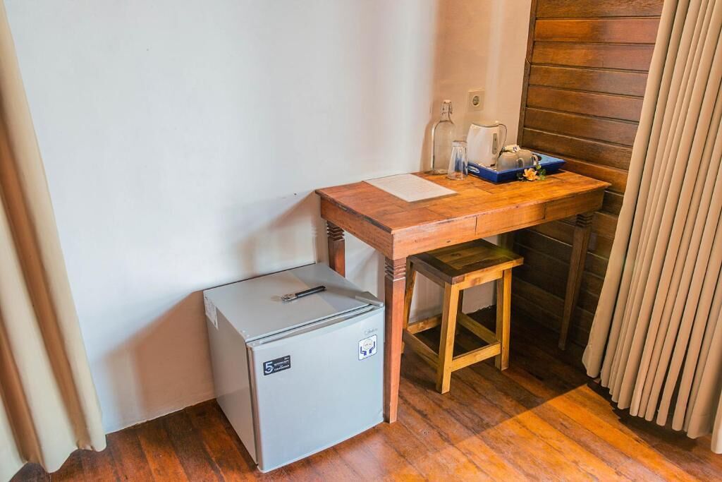 Een compacte kamer met een houten bureau, een kleine koelkast en een radiator.