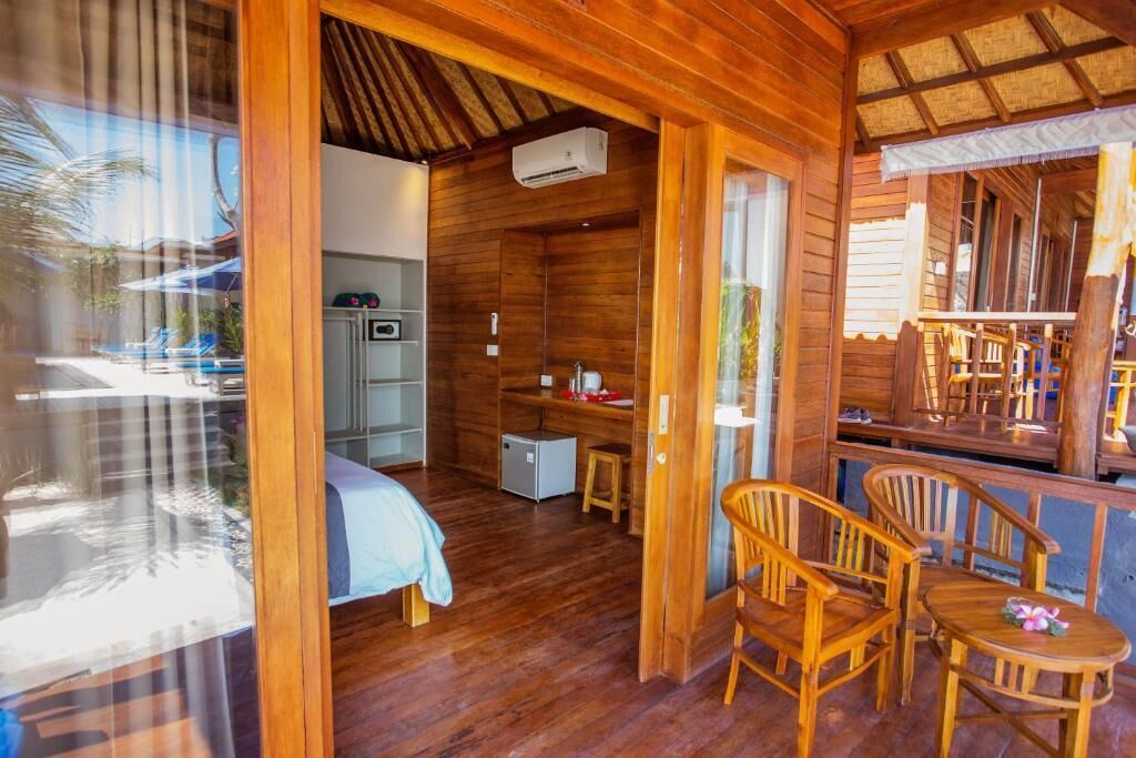 A wooden cabin with a bed, a small kitchenette, and a dining area with chairs.