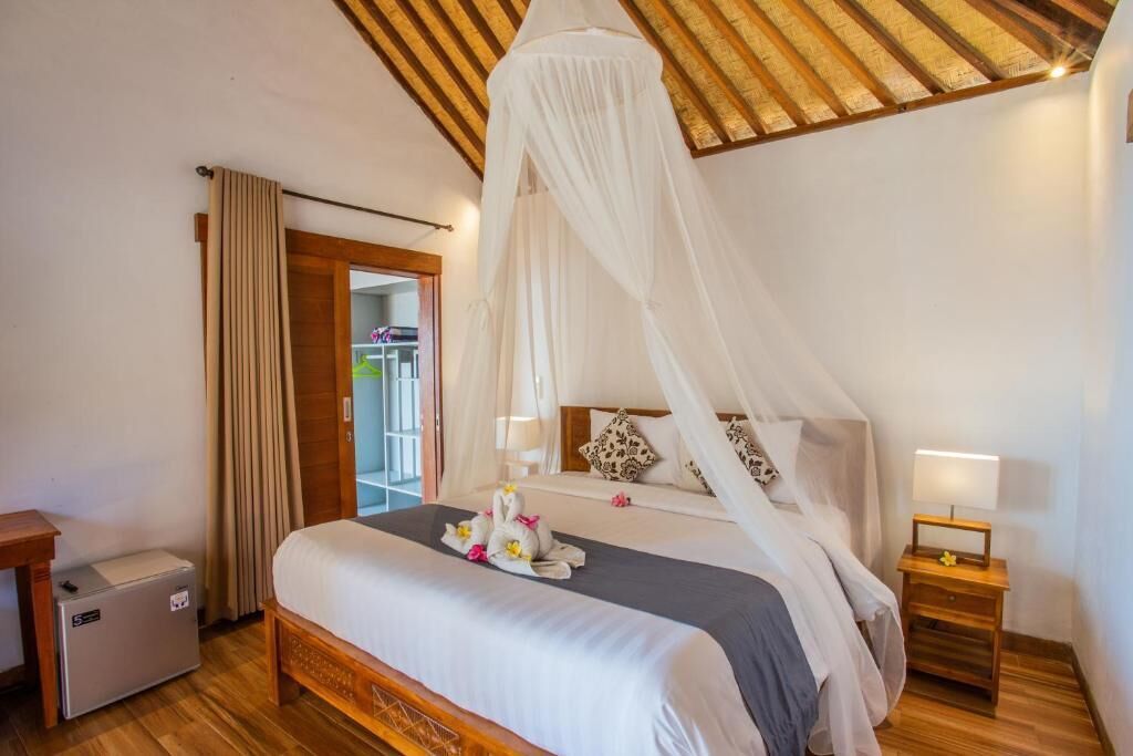 A bedroom with a canopy bed, a bedside table with a lamp, and a small bedside table with a lamp.