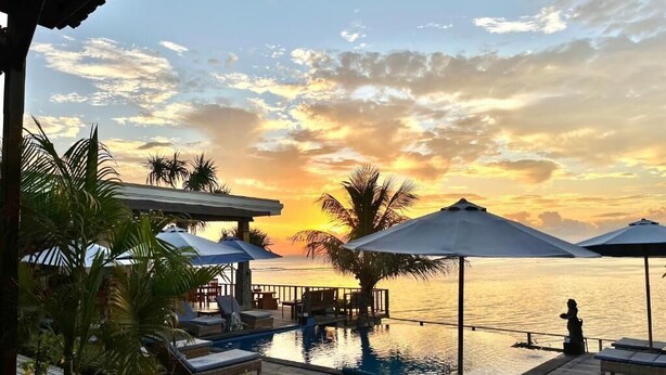 A poolside area with lounge chairs and umbrellas, overlooking a body of water during sunset. - Nusa Veranda Sunset Villas & Restaurant (Ceningan Island)