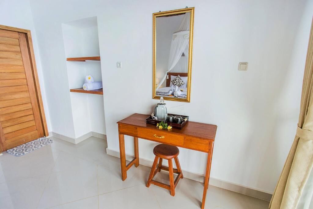 Una habitación con un escritorio de madera, un taburete, un espejo y una cama con dosel.