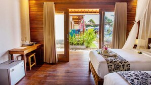 A hotel room with a wooden ceiling, a bed with a floral bedspread, a desk with a computer, and a view of the outdoor area. - Nusa Veranda Sunset Villas & Restaurant (Ceningan Island)