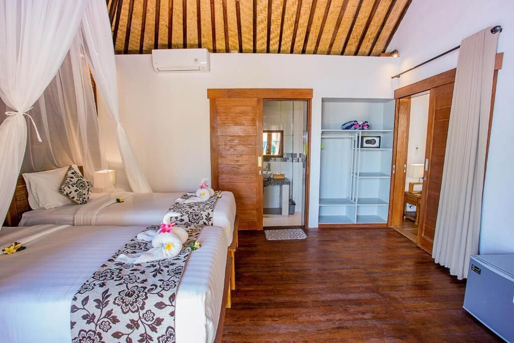 A bedroom with two beds, a wooden ceiling, and a wardrobe.