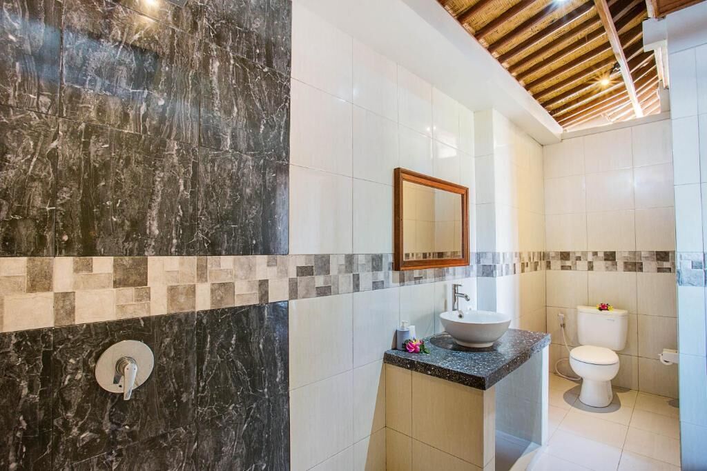 Un baño con pared de mármol, un lavabo, un inodoro y techo de madera.