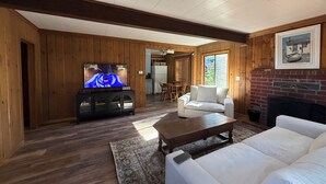 Un salon avec une télévision, un canapé blanc et une cheminée.